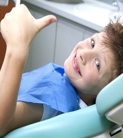 Boy smiling with thumb's up in dental chair