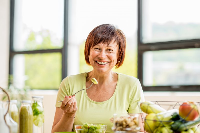 Older patient smiling with dentures while eating