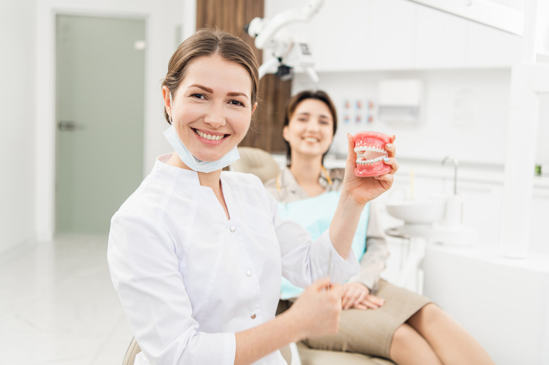 Dentist showing younger patient dentures